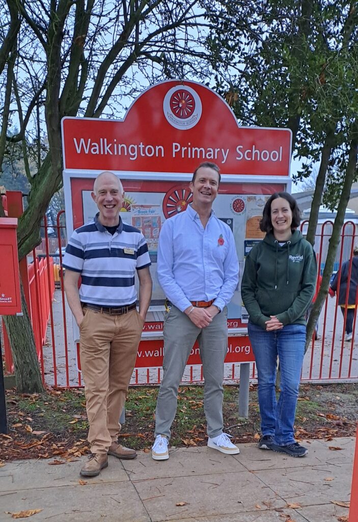 Richard Berry (Let's Go Zero) Chris Bullough (Headteacher) and Clare Collins (Climate Ambassador and parent) standing outside the school gates smiling